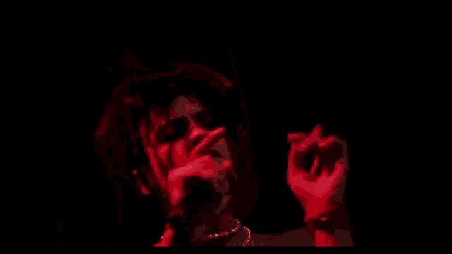 a man without a shirt is singing into a microphone on a stage in a dark room .