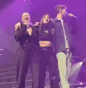 a person is singing into a microphone on a stage in a purple light .
