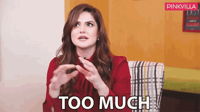 a woman in a red shirt is sitting in a chair with her hands out and says too much .