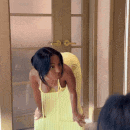 a woman in a yellow dress is looking at herself in a mirror .