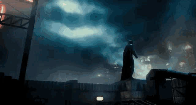 a statue of batman is standing on top of a building in a dark city .