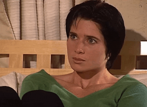 a woman in a green sweater sits on a bed