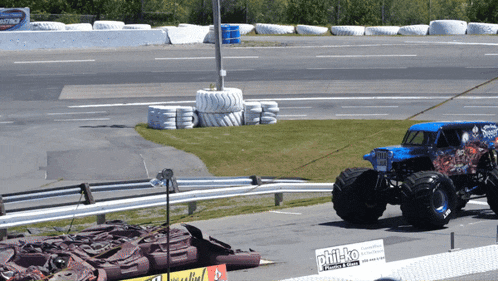 a monster truck is parked on the side of the road next to a sign that says philko