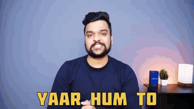 a man with a beard says yaar hum to in front of a blue wall
