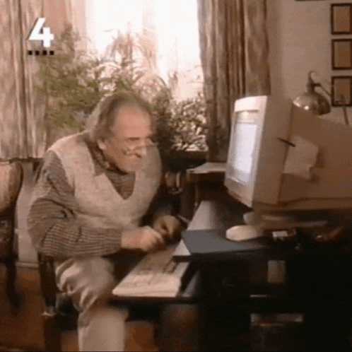 an old man sits at a desk in front of a computer with the number 4 on the bottom right