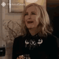 a woman in a black shirt is holding a glass of wine and smiling .