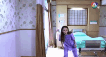a woman in purple pajamas is standing in a hospital room .