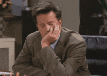 a man in a suit with his hand on his face