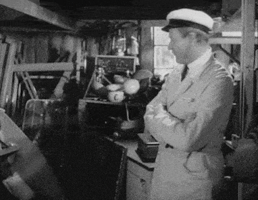 a black and white photo of a man in a white coat and hat with the letter c on his chest