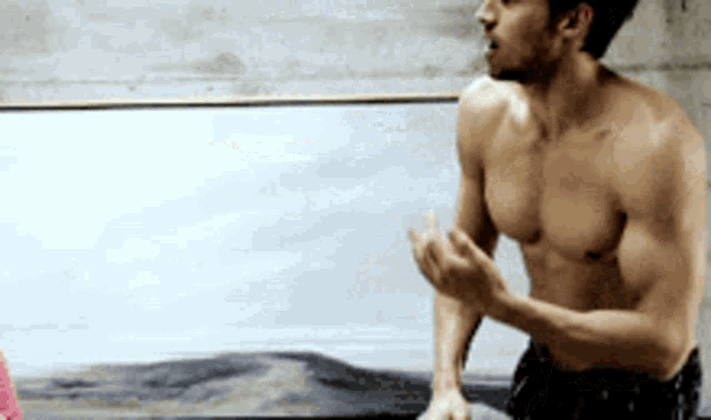 a shirtless man stands in front of a painting