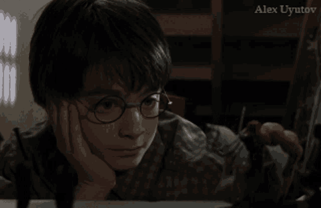 a young boy with glasses is looking at something with alex uyutov written on the bottom