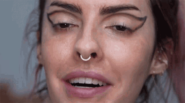 a close up of a woman 's face with a piercing in her nose