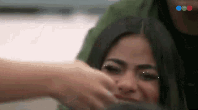 a woman 's face is being touched by a man 's hand while another woman looks on .