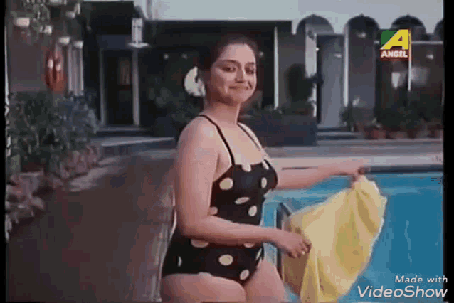 a woman in a polka dot bikini is standing next to a swimming pool .