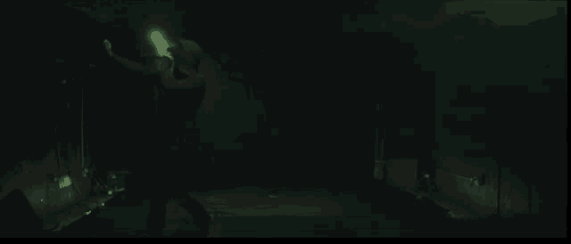 a man singing into a microphone in a dark room .