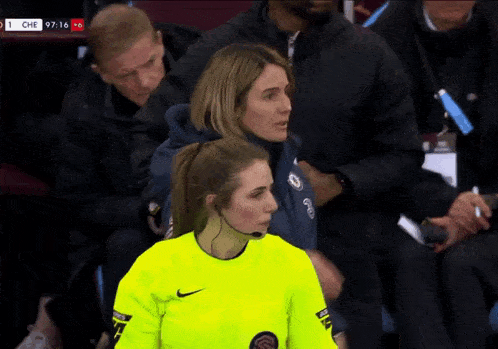 a woman in a yellow nike shirt stands in a stadium