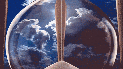 a hourglass with a blue sky and clouds behind it
