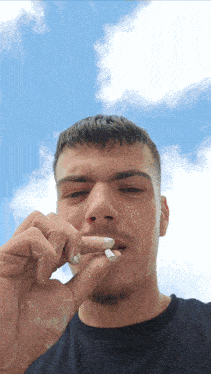 a man in a black shirt is smoking a cigarette