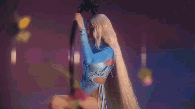 a woman with blonde hair is hanging from a hoop with flowers falling around her