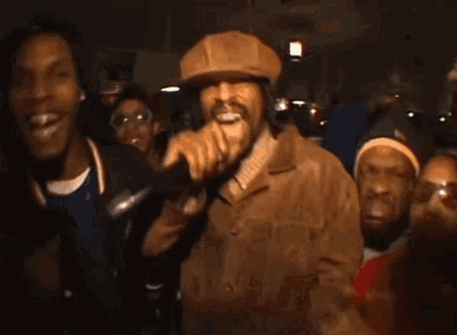 a man in a hat is singing into a microphone in front of a crowd with a shirt that says six on it .