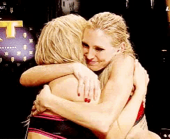 two women hugging each other in front of a sign that says t on it