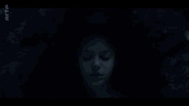 a close up of a woman 's face in the dark with a shocked look on her face .