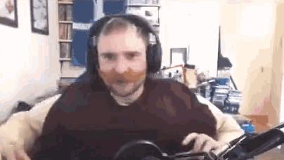 a man with a mustache and headphones is playing a guitar in a room .