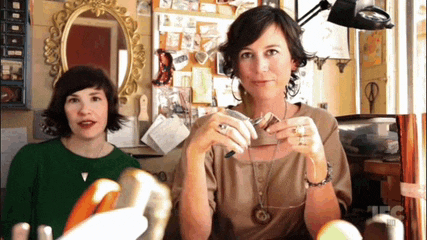 two women are sitting in front of a mirror with the letters jfc on the bottom right