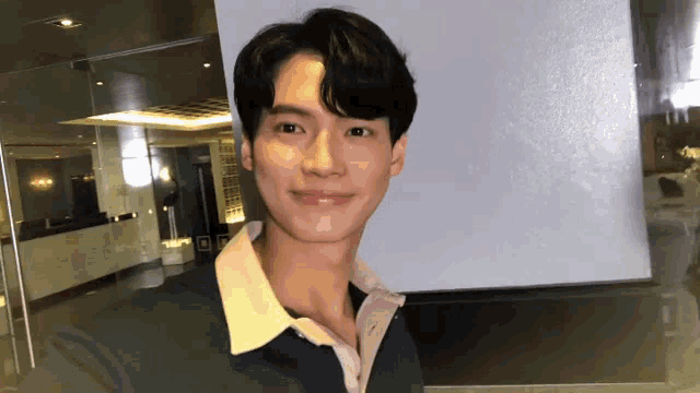 a young man wearing a green shirt and a pink shirt is smiling for the camera .