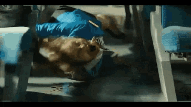 a man in a blue jacket is laying on the floor of a plane