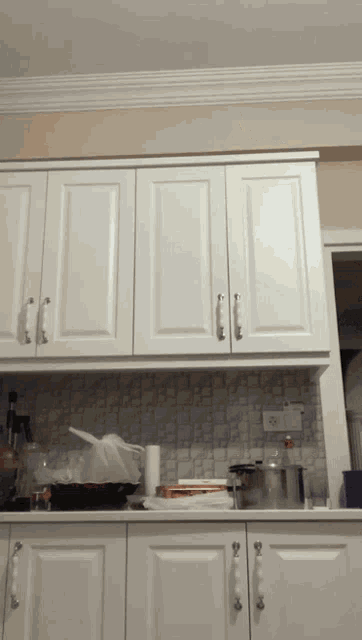 a kitchen with white cabinets and white handles and a white counter top