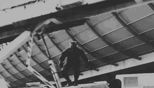 a black and white photo of a man standing on top of a building with a sign that says banghy