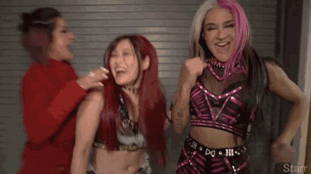 a group of female wrestlers are standing next to each other in a room .