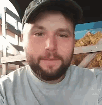 a man with a beard wearing a hat and a white shirt .