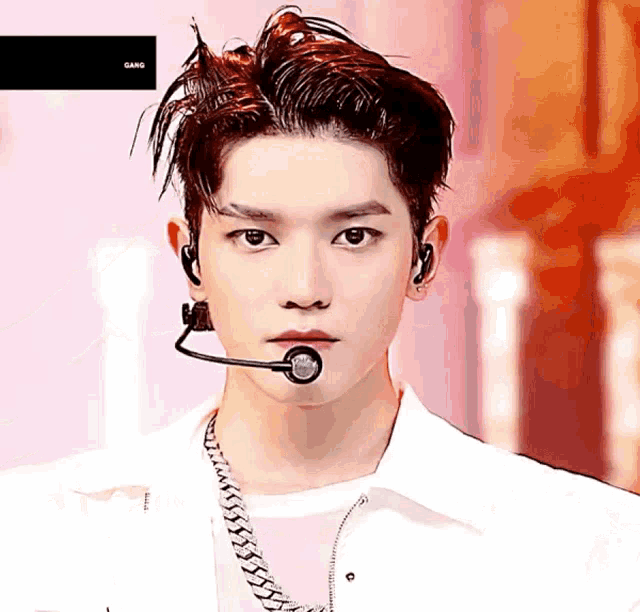 a close up of a man wearing a microphone with the word gang on the bottom left