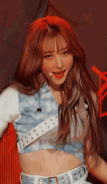 a woman with red hair is wearing a crop top and white belt