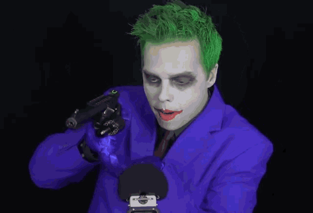 a man dressed as the joker holds a gun