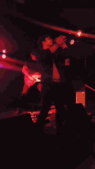 a man singing into a microphone while another man plays guitar