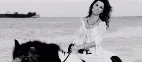 a woman is riding a horse on the beach .