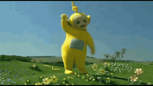 a yellow teddy bear is standing in a field of flowers .