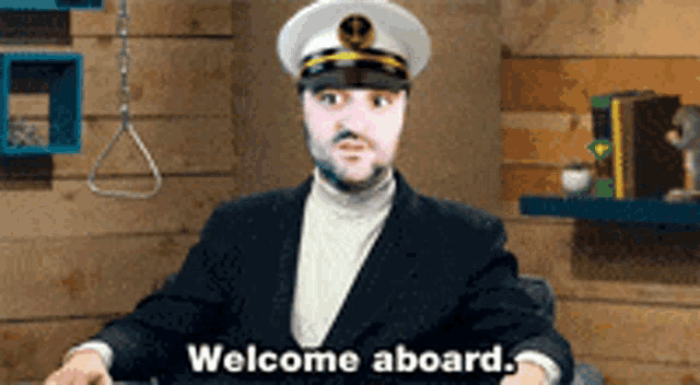 a man in a captain 's hat is sitting in front of a sign that says welcome aboard
