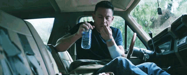 a man sitting in the back seat of a car drinking water from a bottle