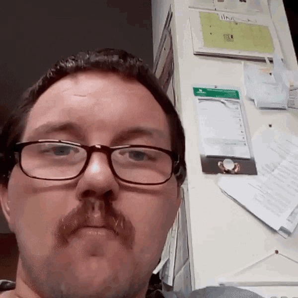 a man wearing glasses and a mustache is taking a picture