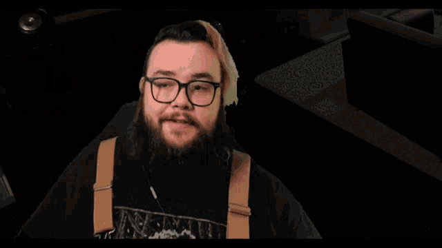 a man with a beard and pink hair is wearing overalls and a black shirt that says ' nightmare ' on it