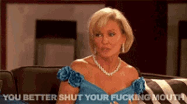 a woman in a blue dress is sitting on a couch and saying you better shut your fucking mouth