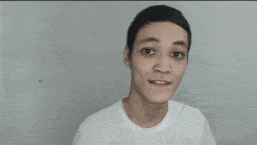 a young man wearing a white t-shirt is looking at the camera and making a funny face .