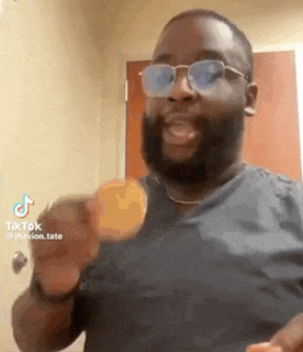a man with a beard and glasses is holding a piece of food in his hand .