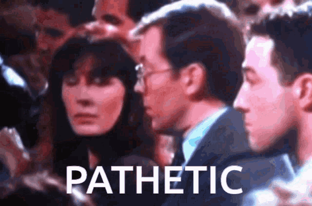 a man and a woman are sitting in a crowd with the word pathetic written on the screen