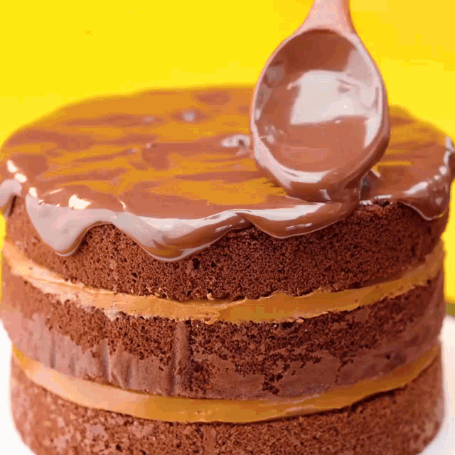 a chocolate cake is being frosted with chocolate icing