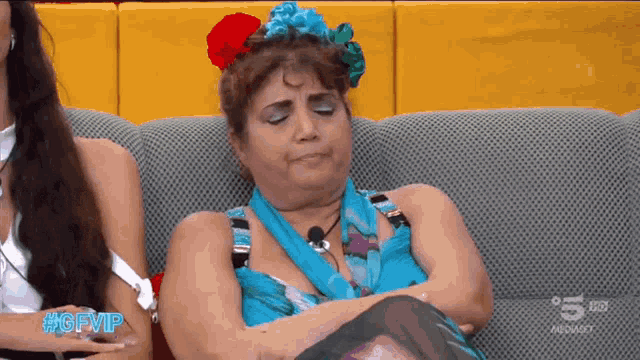 a woman with a flower in her hair is sitting on a couch with the hashtag #gfvip on the bottom